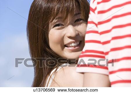 Stock Photo - Young couple on beach, woman smiling and looking back, Saipan, USA . Fotosearch