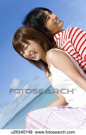 Stock Photo - Young couple sitting on beach, back to back, Saipan, USA . Fotosearch