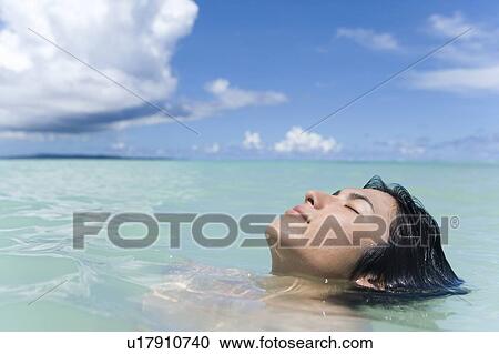 Stock Image - Young man in the sea, closing eyes, Saipan, USA . Fotosearch