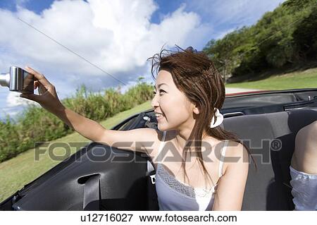 Young woman holding a digital camera in the car, smiling, Saipan, USA View Large Photo Image Stock Photo - Young woman holding a digital camera in the car, smiling, Saipan, USA . Fotosearch