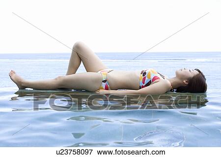 Stock Photo - Young woman in a bikini lying on water, Saipan. Fotosearch