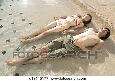 Stock Photo - Young couple lying in swimming pool, Saipan. Fotosearch