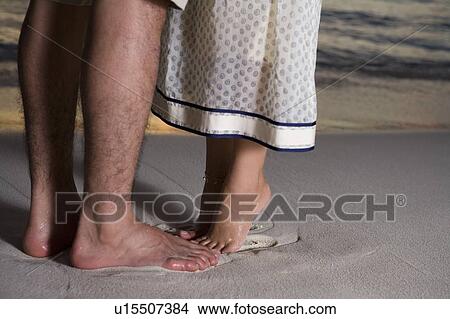 Picture - Young couple on beach, woman standing on toes, Saipan, USA . Fotosearch