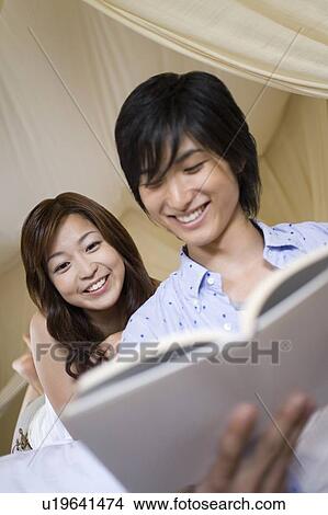 Picture - Young couple reading a book, Saipan. Fotosearch