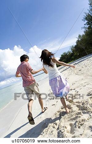 Young couple running on beach, hand in hand, Saipan, USA View Large Photo Image Stock Photo - Young couple running on beach, hand in hand, Saipan, USA . Fotosearch