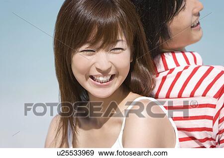 Stock Photo - Young couple sitting on beach, back to back, smiling, Saipan, USA . Fotosearch