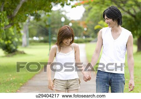 Stock Photo - Young couple smiling and walking hand in hand, differential focus, Saipan, USA . Fotosearch
