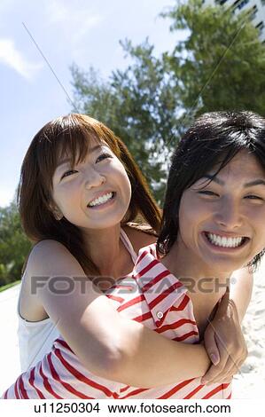 Picture - Young woman embracing man from back, smiling, Saipan, USA . Fotosearch