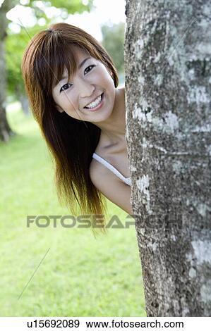 Portrait of a young woman standing behind a tree, smiling, Saipan, USA View Large Photo Image Stock Photo - Portrait of a young woman standing behind a tree, smiling, Saipan, USA . Fotosearch