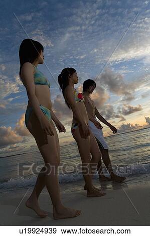 Stock Photo - Three young people walking on beach in the evening, Saipan, USA . Fotosearch
