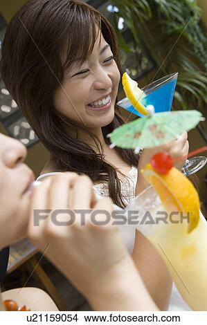 Picture - Yong women drinking cocktail, Saipan, Differential Focus. Fotosearch
