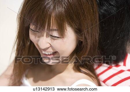 Stock Image - Young couple sitting on beach, back to back, smiling, Saipan, USA . Fotosearch