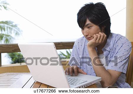 Stock Photograph - Young man using a laptop, Saipan. Fotosearch