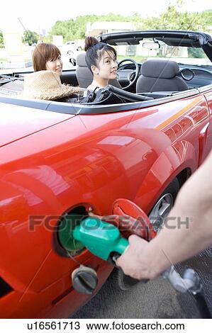 Stock Image - Young people in gas station, man filling car, Saipan, USA . Fotosearch