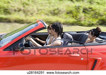 Stock Image - Young people in the car, man driving, panning, Saipan, USA . Fotosearch
