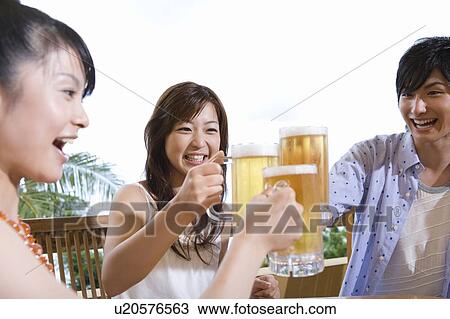 Stock Image - Young people toasting with beer, Saipan. Fotosearch