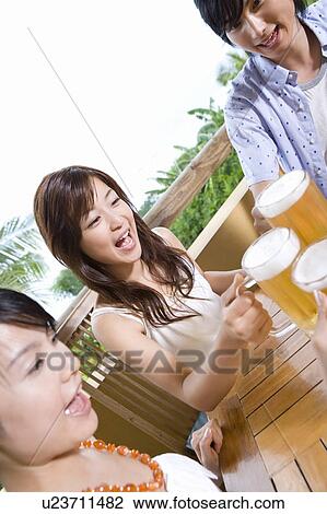 Stock Image - Young people toasting with beer, Saipan. Fotosearch