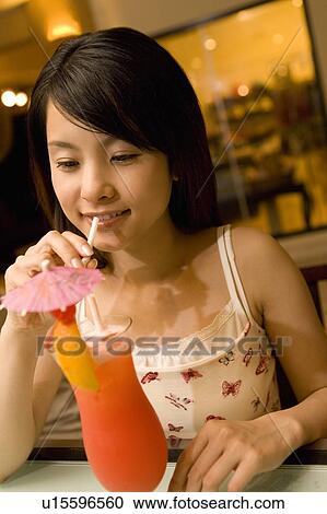 Stock Image - Young woman drinking a cocktail, Saipan. Fotosearch