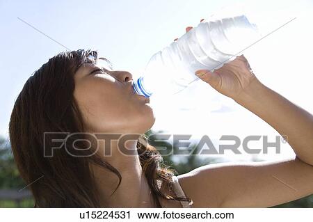 Stock Image - Young woman drinking water, Saipan. Fotosearch