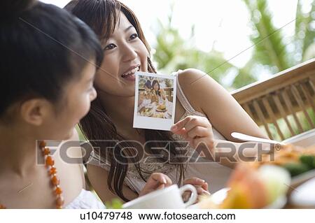 Stock Photo - Young woman holding a photograph, Saipan, Differential Focus. Fotosearch