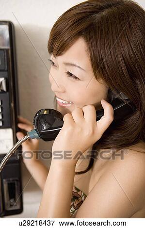 Stock Photo - Young woman using a public phone, Saipan. Fotosearch