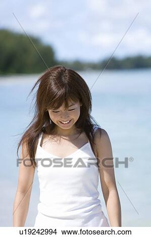 Picture - Young woman walking on beach, smiling, differential focus, Saipan, USA . Fotosearch