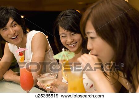 Stock Photo - Friends drinking cocktail, Saipan, Focus on Background. Fotosearch