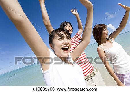 Three young people smiling and raising arms on beach, Saipan, USA View Large Photo Image Stock Image - Three young people smiling and raising arms on beach, Saipan, USA . Fotosearch