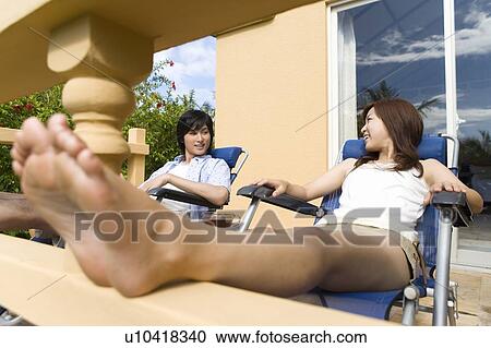 Stock Image - Young couple relaxing at balcony, Saipan. Fotosearch