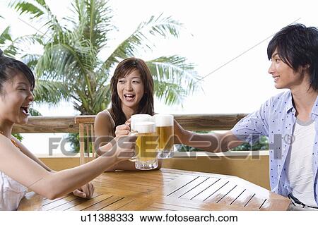 Stock Image - Young people toasting with beer, Saipan. Fotosearch