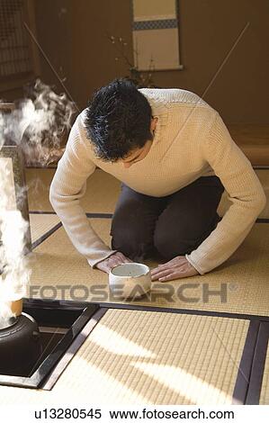 Stock Photography - Man attending Japanese tea ceremony, bending over, front view, Japan. Fotosearch