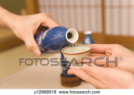 Man pouring Sake into a Sake cup for woman, side view, close up, differential focus, Japan View Large Photo Image Stock Photo - Man pouring Sake into a Sake cup for woman, side view, close up, differential focus, Japan. Fotosearch