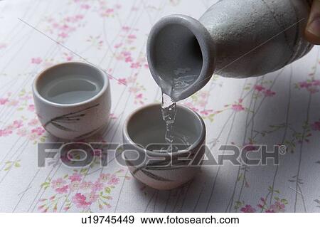 Man pouring Sake into Sake cup, high angle view, close up, Japan View Large Photo Image Stock Photo - Man pouring Sake into Sake cup, high angle view, close up, Japan. Fotosearch