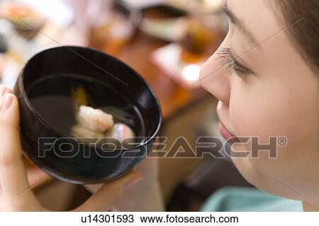 Stock Image - Woman holding bowl of soup, high angle view, close up, Japan. Fotosearch