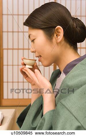 Stock Photography - Woman in Yukata drinking Sake, side view, Japan. Fotosearch