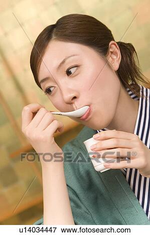 Stock Photo - Woman in Yukata eating egg hotchpotch, front view, Japan. Fotosearch