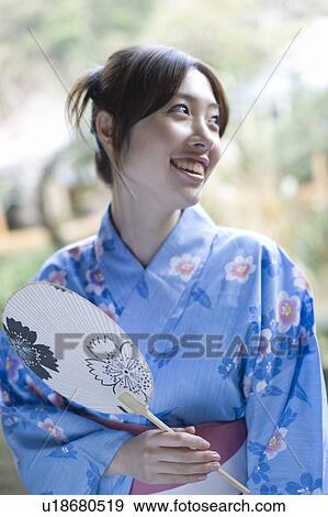 Woman in Yukata holding a Japanese fan, looking away, front view, Japan View Large Photo Image Stock Photo - Woman in Yukata holding a Japanese fan, looking away, front view, Japan. Fotosearch