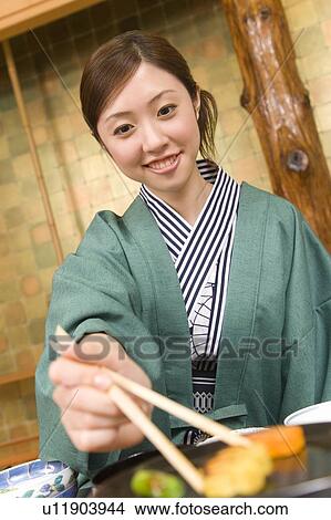 Picture - Woman smiling and holding chopsticks, front view, Japan. Fotosearch