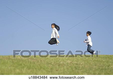 Picture - Boy and Girl jumping on grass. Fotosearch