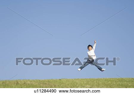 Stock Image - Boy jumping on grass. Fotosearch