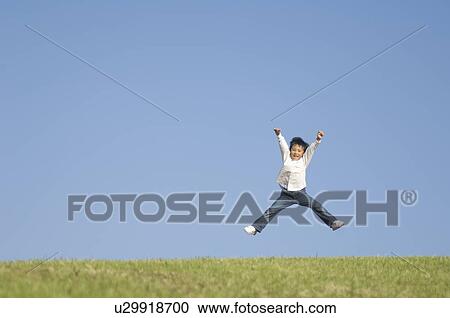 Stock Image - Boy jumping on grass. Fotosearch