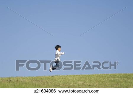 Stock Photograph - Boy jumping on grass. Fotosearch