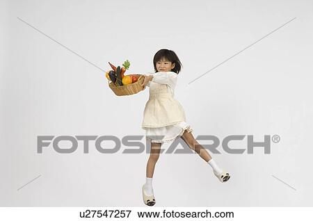 Stock Photo - Girl holding vegetable in basket. Fotosearch