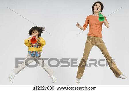 Stock Photograph - Mother and daughter cheering with megaphone. Fotosearch