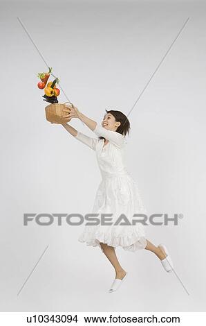Picture - Young woman holding vegetable in basket. Fotosearch