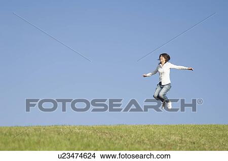 Picture - Young woman jumping on grass. Fotosearch