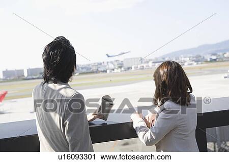 Stock Image - Business people standing at airport. Fotosearch