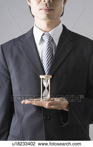 Stock Image - Businessman holding sand clock. Fotosearch