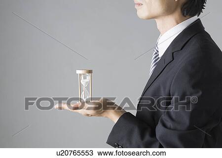 Businessman holding sand clock View Large Photo Image Stock Image - Businessman holding sand clock. Fotosearch