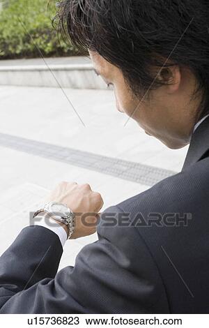 Businessman looking at wristwatch View Large Photo Image Stock Image - Businessman looking at wristwatch. Fotosearch